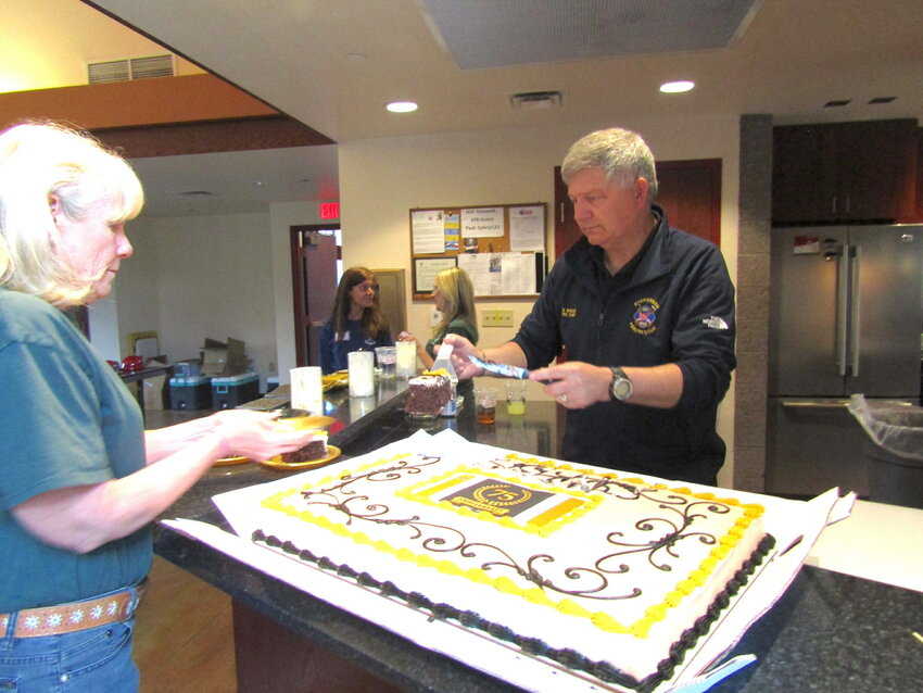 Fire Chief Mike Weege serves up cake, aided by Maureen Hornbecker, at the Evergreen Fire/Rescue 75th anniversary barbecue on May 27.